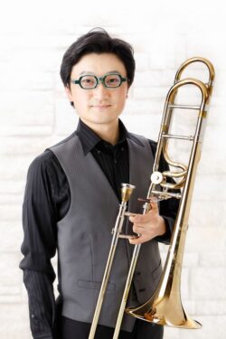 白い背景でトロンボーンを持つ男性トロンボーン奏者「高橋真太郎」さんのプロフィールポートレート